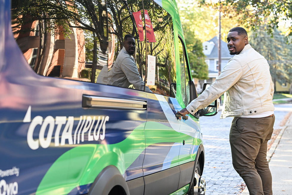 A rider opening the door of a COTA Plus vehicle